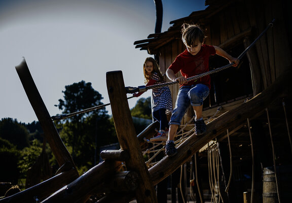 Das Bild zeigt zwei Kinder, die auf einem Klettergerüst eines Spielplatzes beim Freizeitzentrum Peterberg klettern.