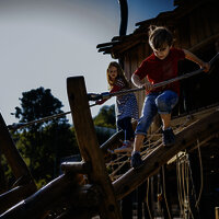 Das Bild zeigt zwei Kinder, die auf einem Klettergerüst eines Spielplatzes beim Freizeitzentrum Peterberg klettern.