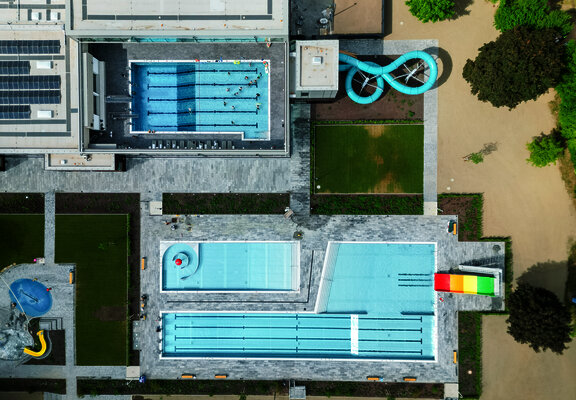 Das Foto zeigt die Gesamtanlage des Vitteliusbad Wittlich, mit Hallenbad, Freibad, Rutschen, Liegewiesen und Kinderbereich.