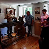 Das Bild zeigt das hauseigene Sägewerk des Hunsrücker Holzmuseums. Um das Wer stehen Personen und begutachten es.