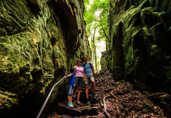 Das Bild zeigt eine Familie auf dem Wanderweg Teufelsschlucht zwischen Felsen.