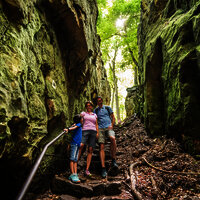 Das Bild zeigt eine Familie auf dem Wanderweg Teufelsschlucht zwischen Felsen.