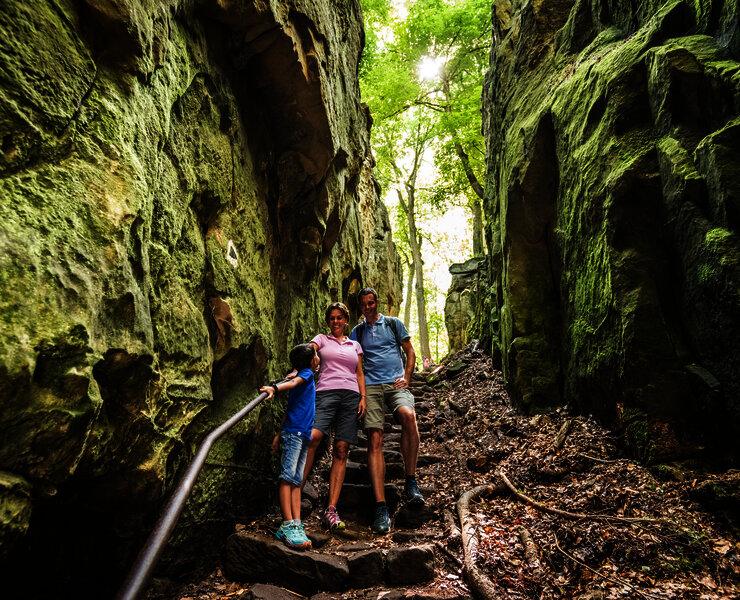 Das Bild zeigt eine Familie auf dem Wanderweg Teufelsschlucht zwischen Felsen.