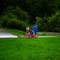 Das Bild zeigt zwei Kinder, die die Sommerrodelbahn beim Freizeitzentrum Peterberg fahren.