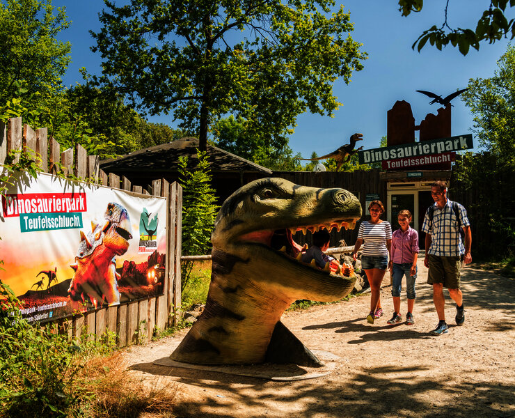 Das Bild zeigt eine Familie im Dinopark Teufelsschlucht.