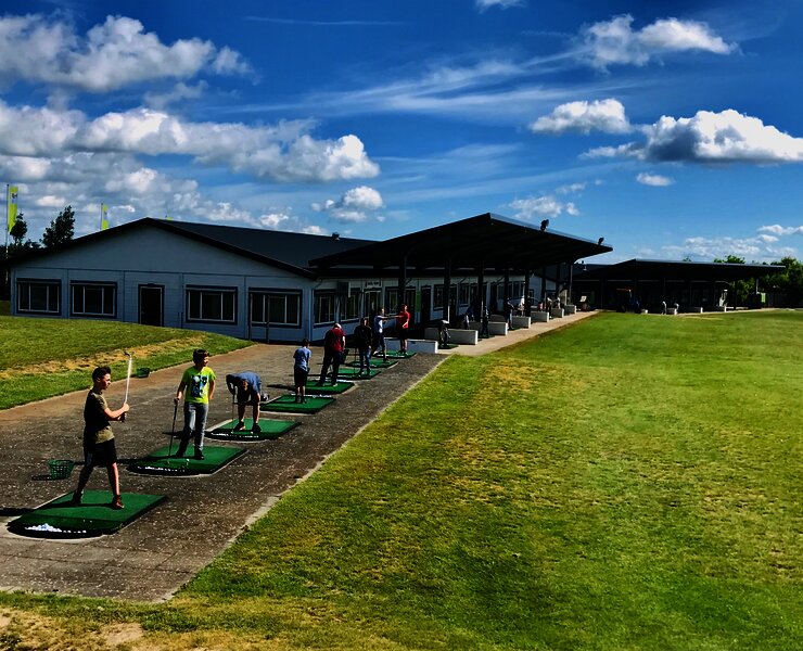 Blick auf die Abschlag Anlage des Golfclub Cochem, auf dem Personen Bälle schwingen.