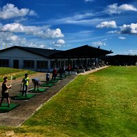 Blick auf die Abschlag Anlage des Golfclub Cochem, auf dem Personen Bälle schwingen.