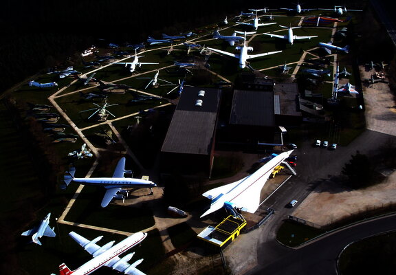 Das Bild zeigt eine Luftaufnahme vom Gelände der Flugausstellung Junior mit zahlreichen Flugzeugen und dem Hauptgebäude.