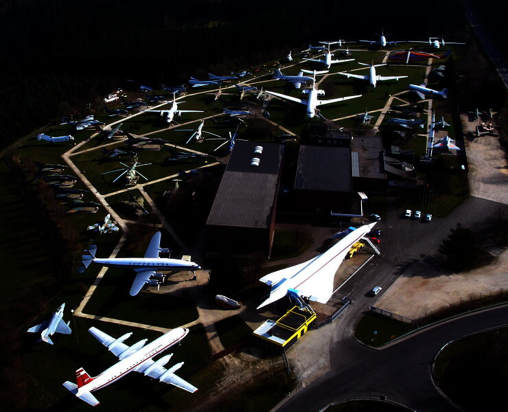 Das Bild zeigt eine Luftaufnahme vom Gelände der Flugausstellung Junior mit zahlreichen Flugzeugen und dem Hauptgebäude.
