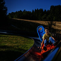 Das Bild zeigt einen Jungen, der die Sommerrodelbahn beim Freizeitzentrum Peterberg fährt.